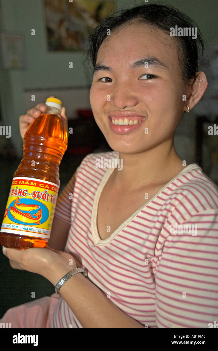 Young woman holds bottle of nuoc mam fermented fish sauce used widely in Vietnamese cooking. Stock Photo