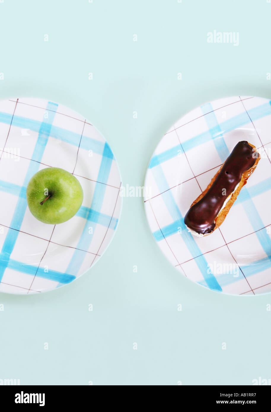 a chocolate eclair and an apple on separate plates Stock Photo