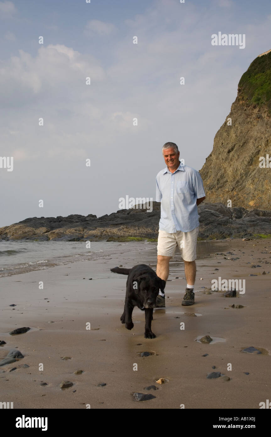 Tresaith beach Cardigan Bay Ceredigion west Wales man walking his black dog summer evening, UK Stock Photo