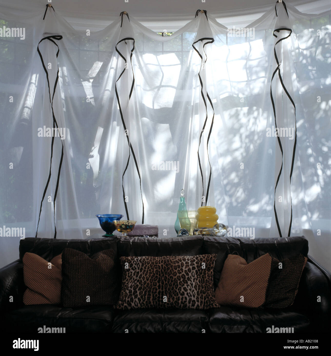 Brown And Leopard Print Cushions On Black Leather Sofa In Front Of