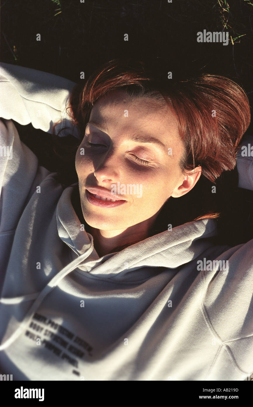 Young woman lying down arms crossed behind her head relaxing Stock