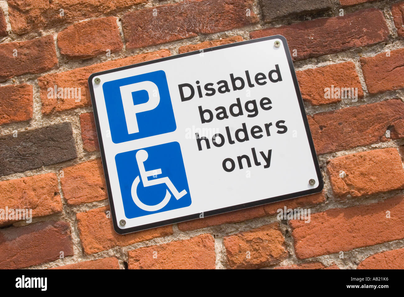Sign on brick wall for Disabled badge holders only car park space Stock
