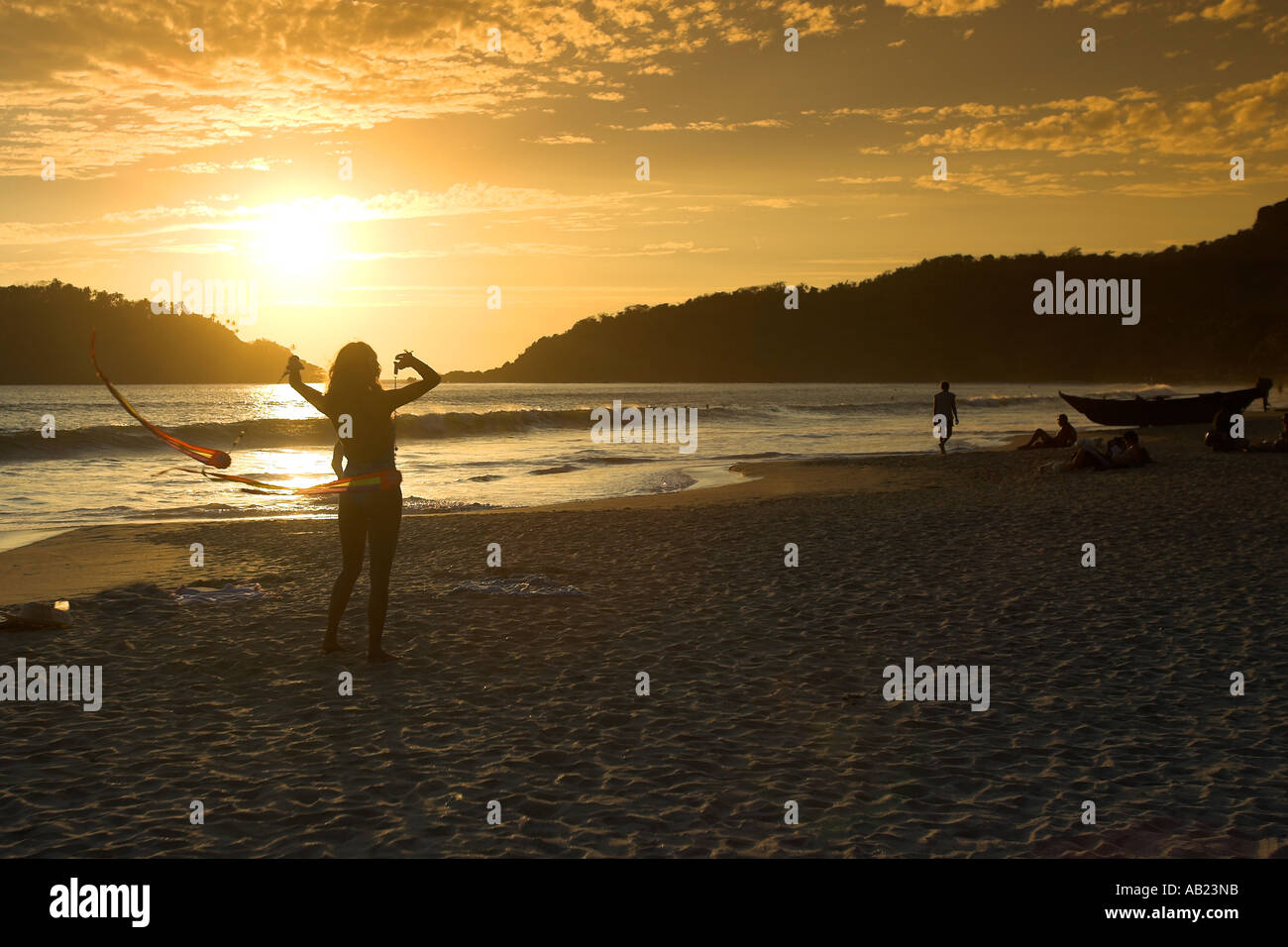 Swimsuit young woman twirling poi ribbons in sunset Palolem Beach south Goa India Stock Photo