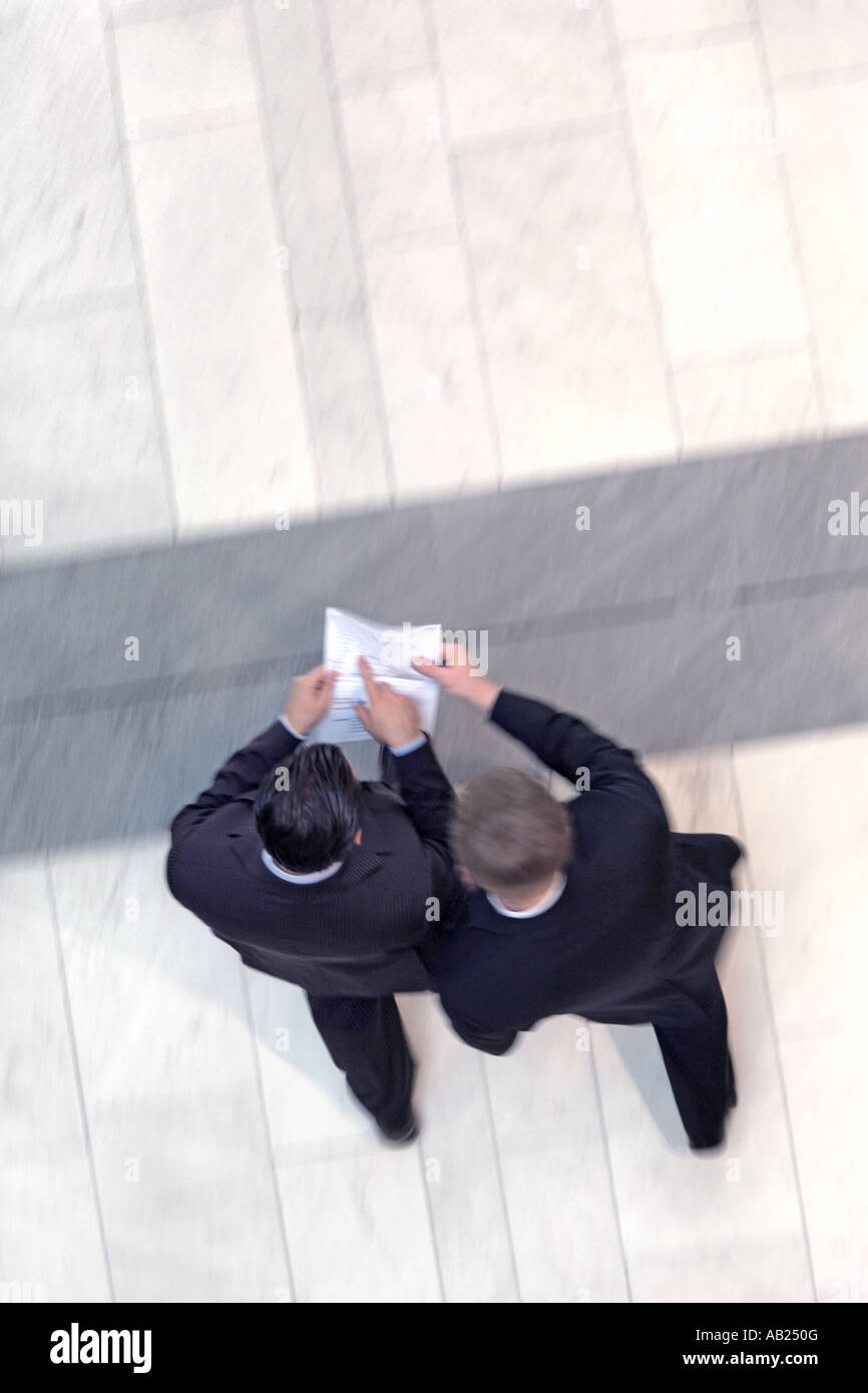 2 manager from above reading something written on a paper 2 Manager von oben die gemeinsam im Gehen ein Dokument lesen Stock Photo