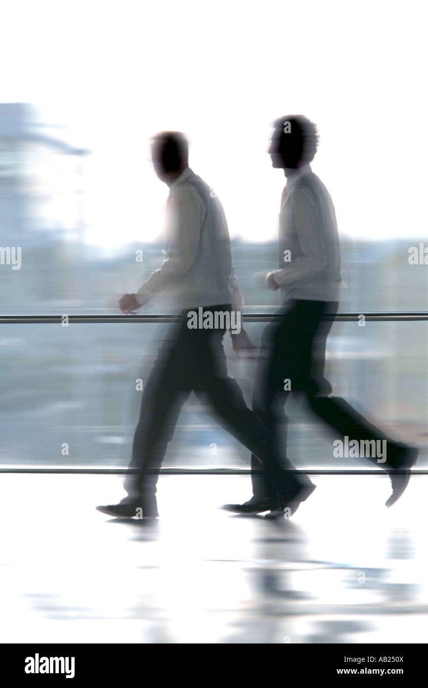 2 Managers are walking in front of a big window 2 Manager im Hemd laufen vor einem großen Fenster Stock Photo
