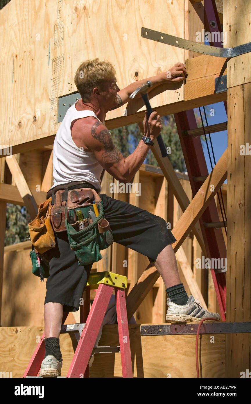 Carpenter hammers in nail during framing process of home construction
