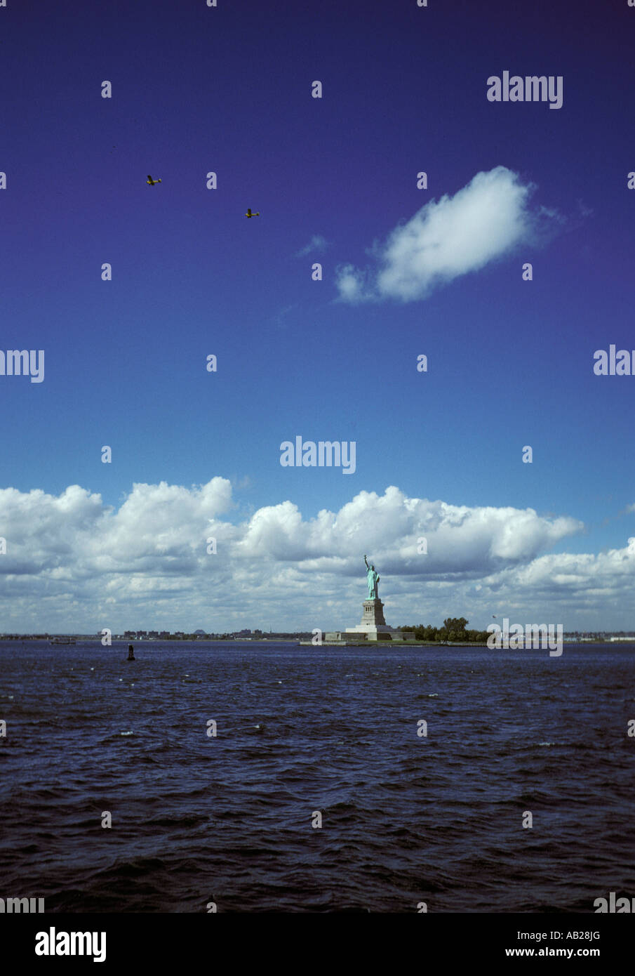 NYC Statue of Liberty New York Harbor New York city USA America Americana bright white fluffy clouds Stock Photo