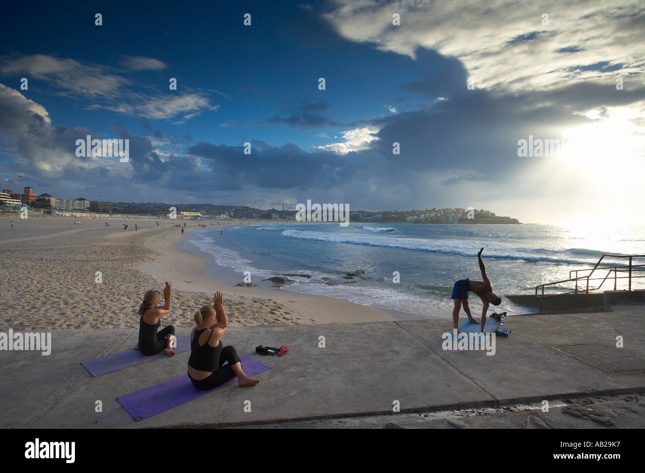 women and man doing exercises on Bondi Beach at dawn Sydney New South Wales Australia Stock Photo