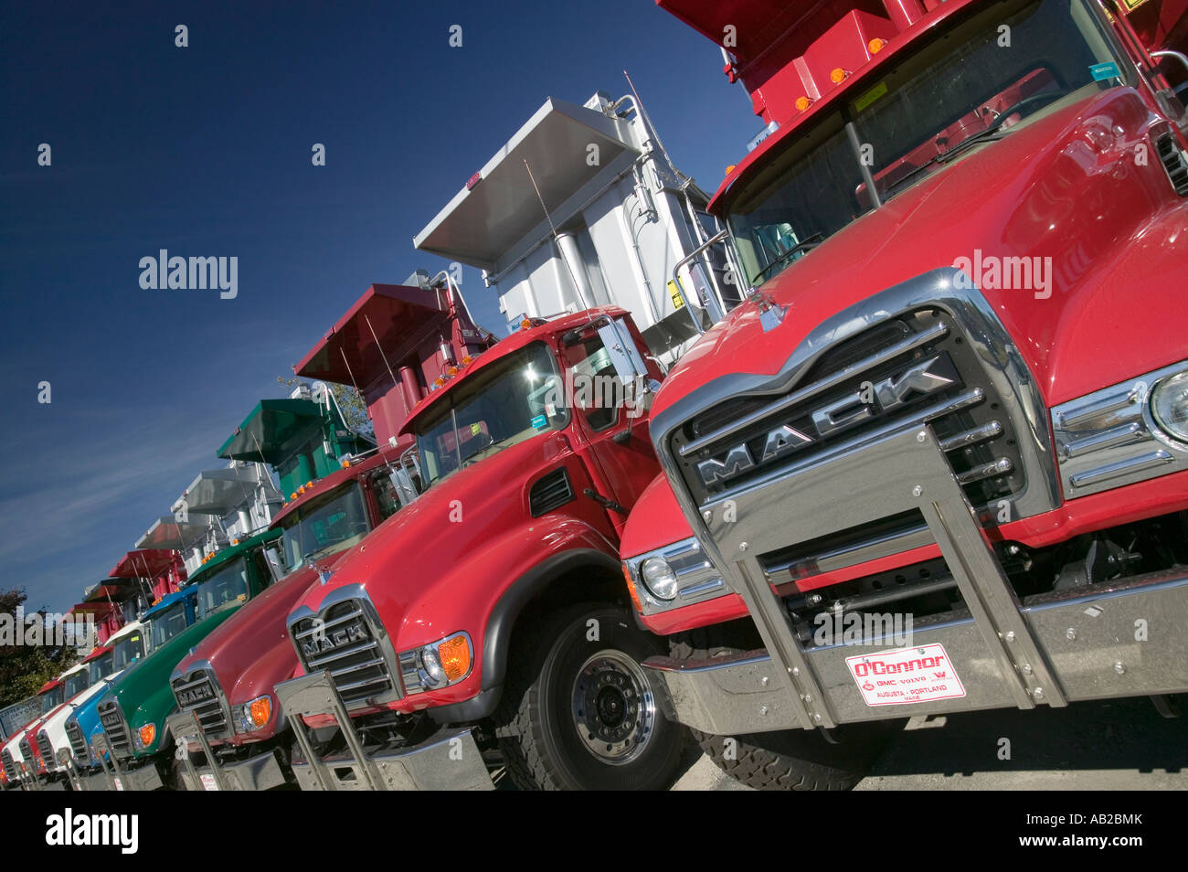 Bright red Mack dump trucks line the road in a row in Maine near the