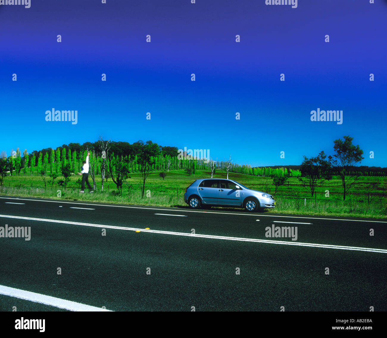 Man jumping near a car at highway Stock Photo