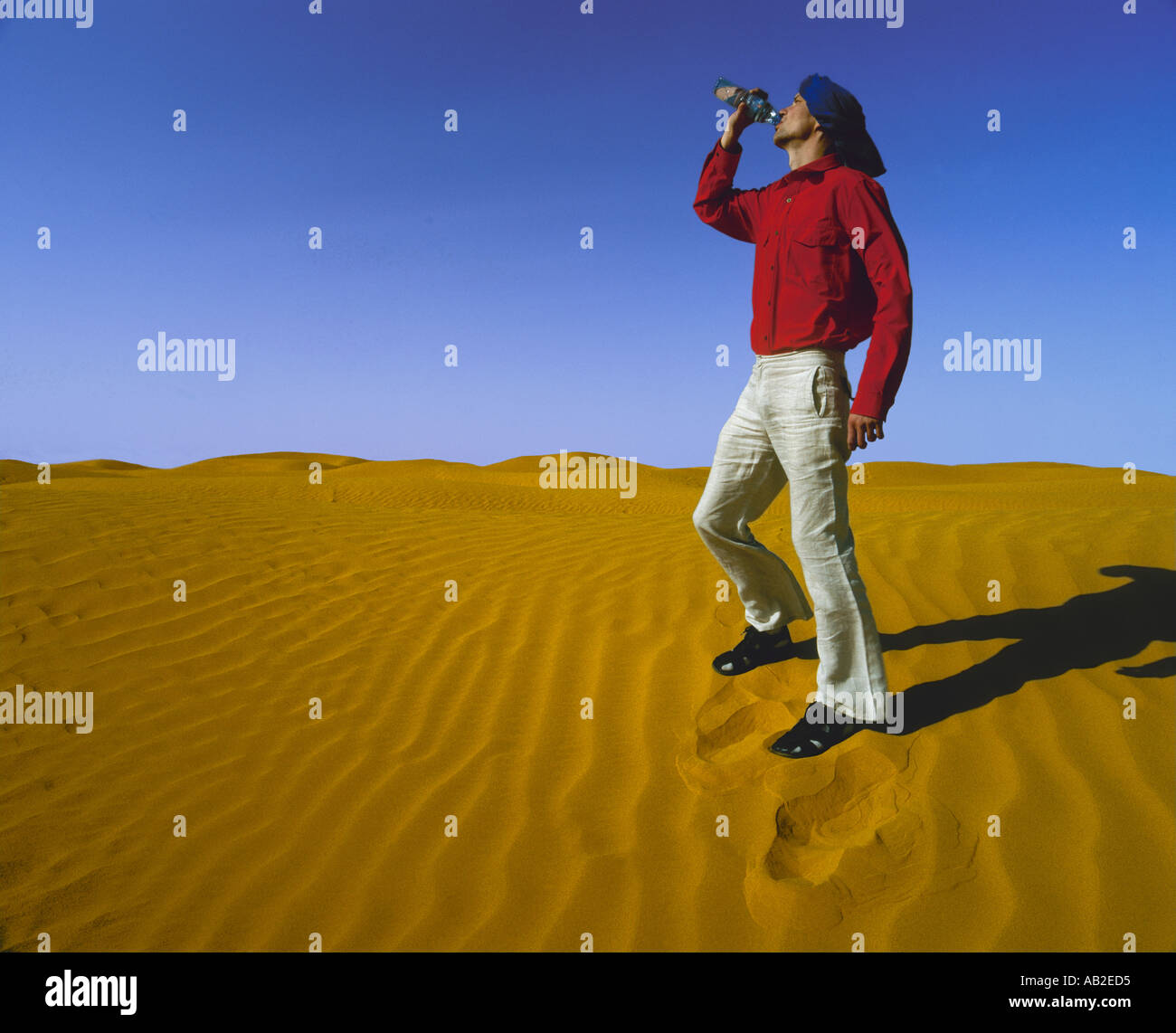 Man drinking water from a bottle in desert Stock Photo