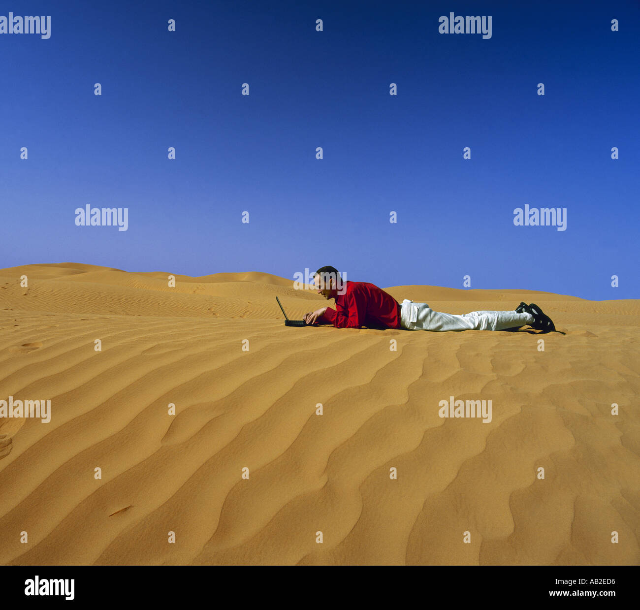 Man lying on the sand in desert with laptop computer Stock Photo - Alamy