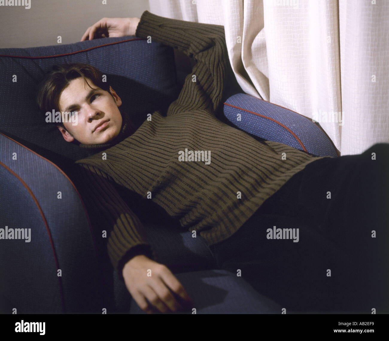 Man lying on armchair Stock Photo