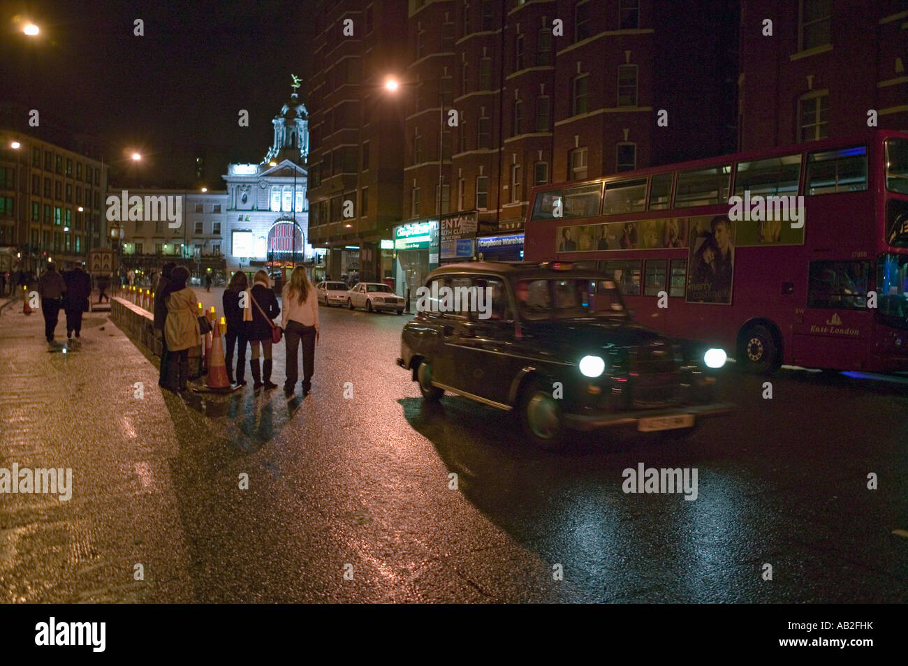Wet night streets of West End of London s theater district with double decker bus and taxi driving by England Stock Photo