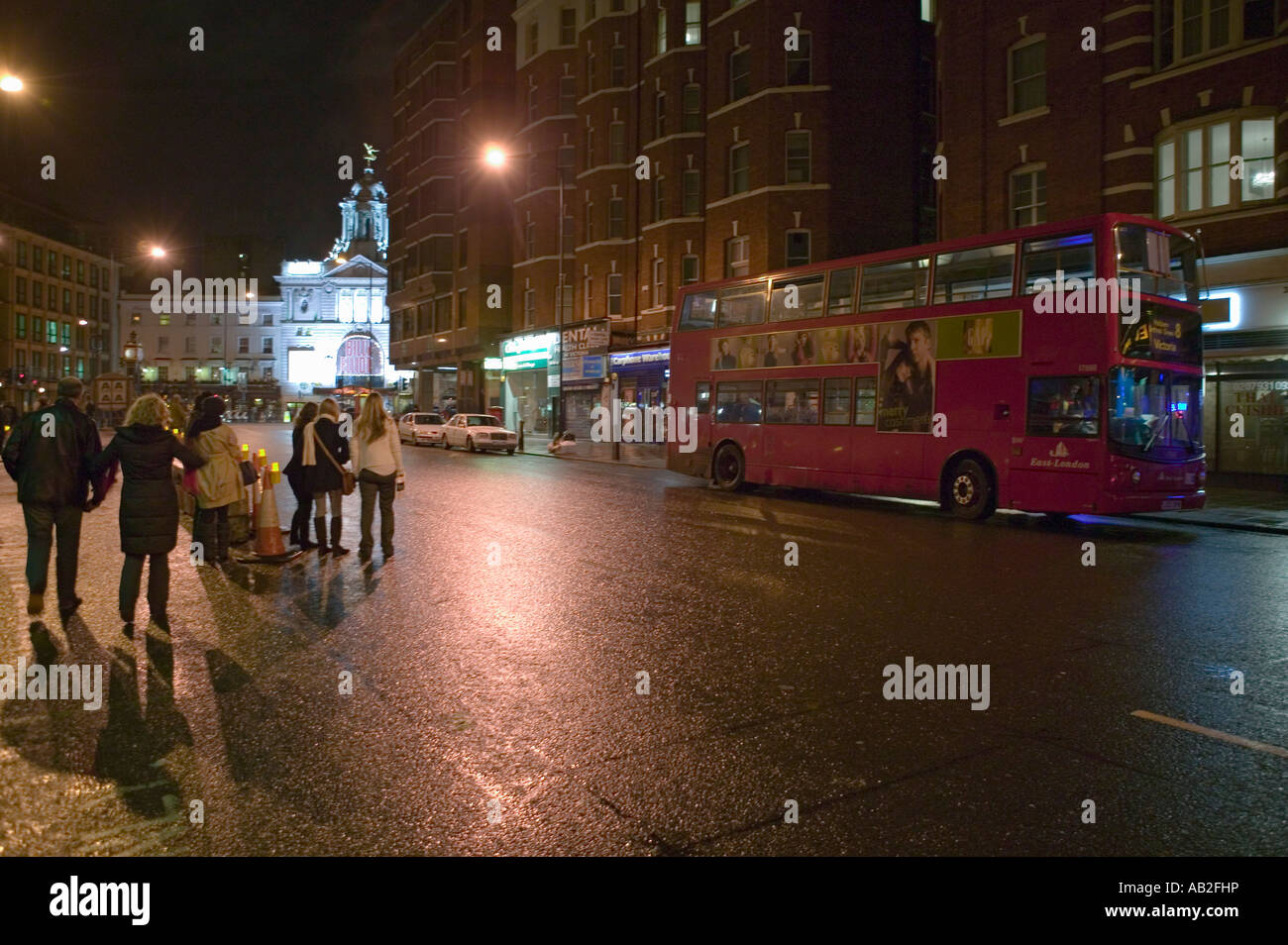 Wet night streets of West End of London s theater district with double decker bus driving by England Stock Photo