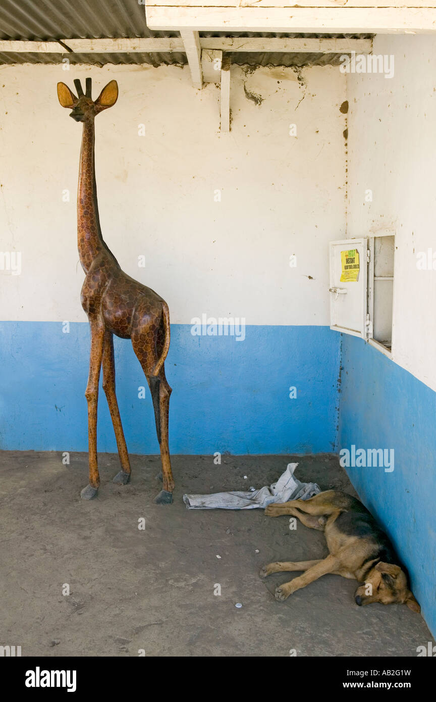 Wooden Giraffe looks over sleeping dog on the way to the Great Rift Valley Kenya Africa Stock Photo