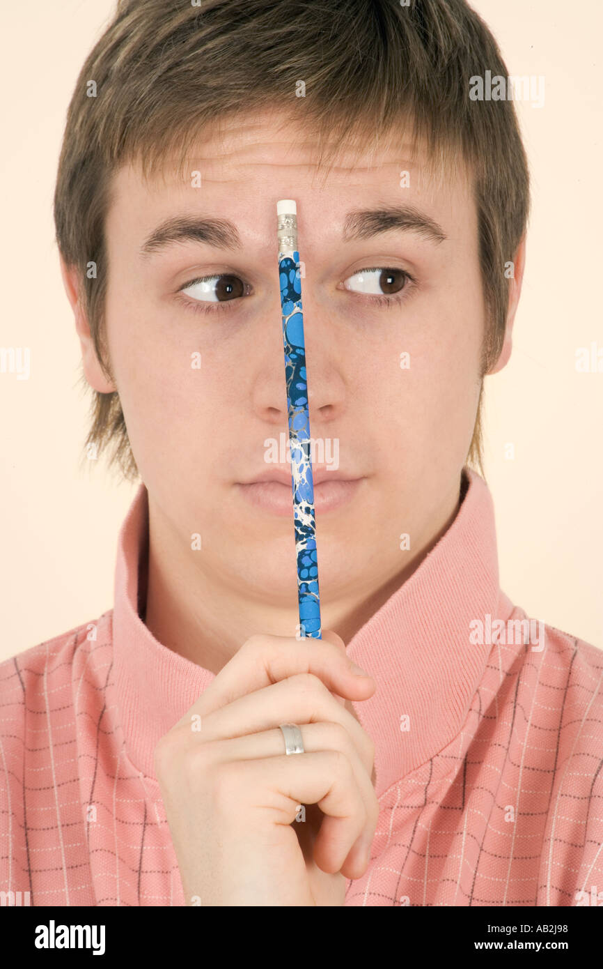 Young man holding pencil to forehead Stock Photo
