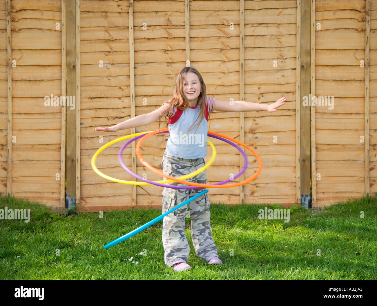 Girl playing with four plastic hula hoops Stock Photo
