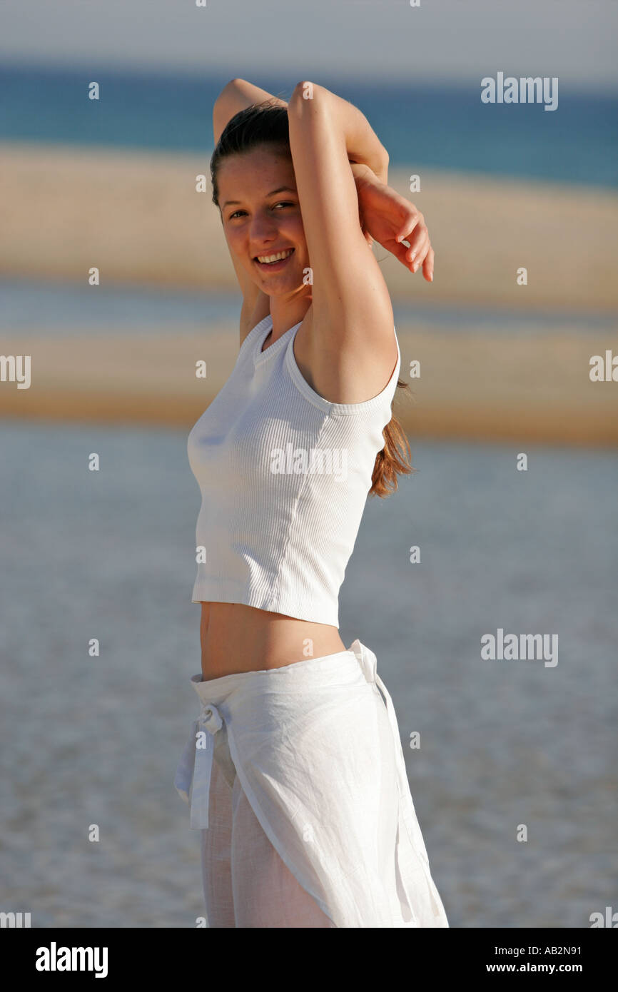 woman-in-white-on-the-beach-smiling-into-the-camera-with-her-arms-AB2N91.jpg