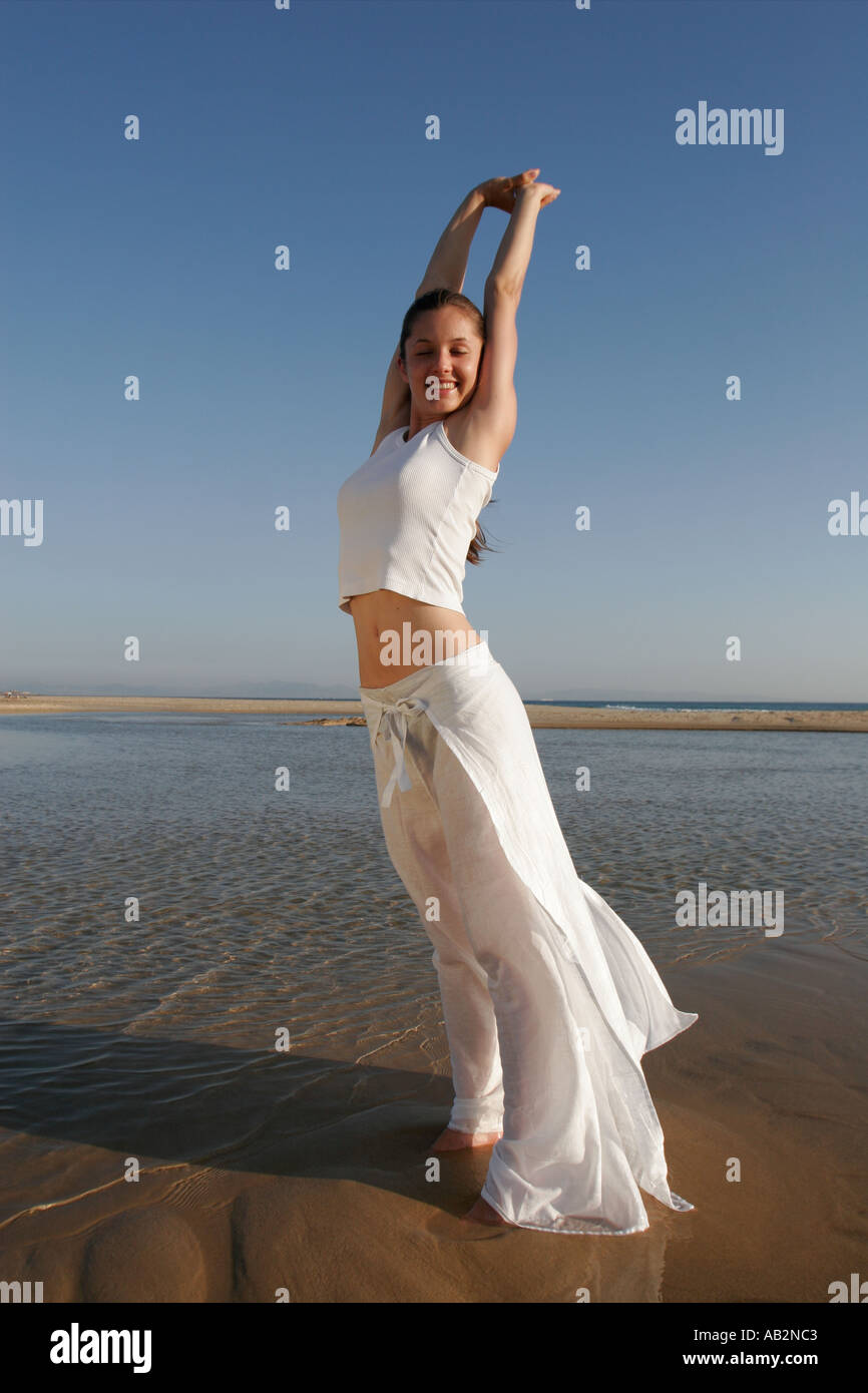 young woman smiling on beach with raised arms Stock Photo