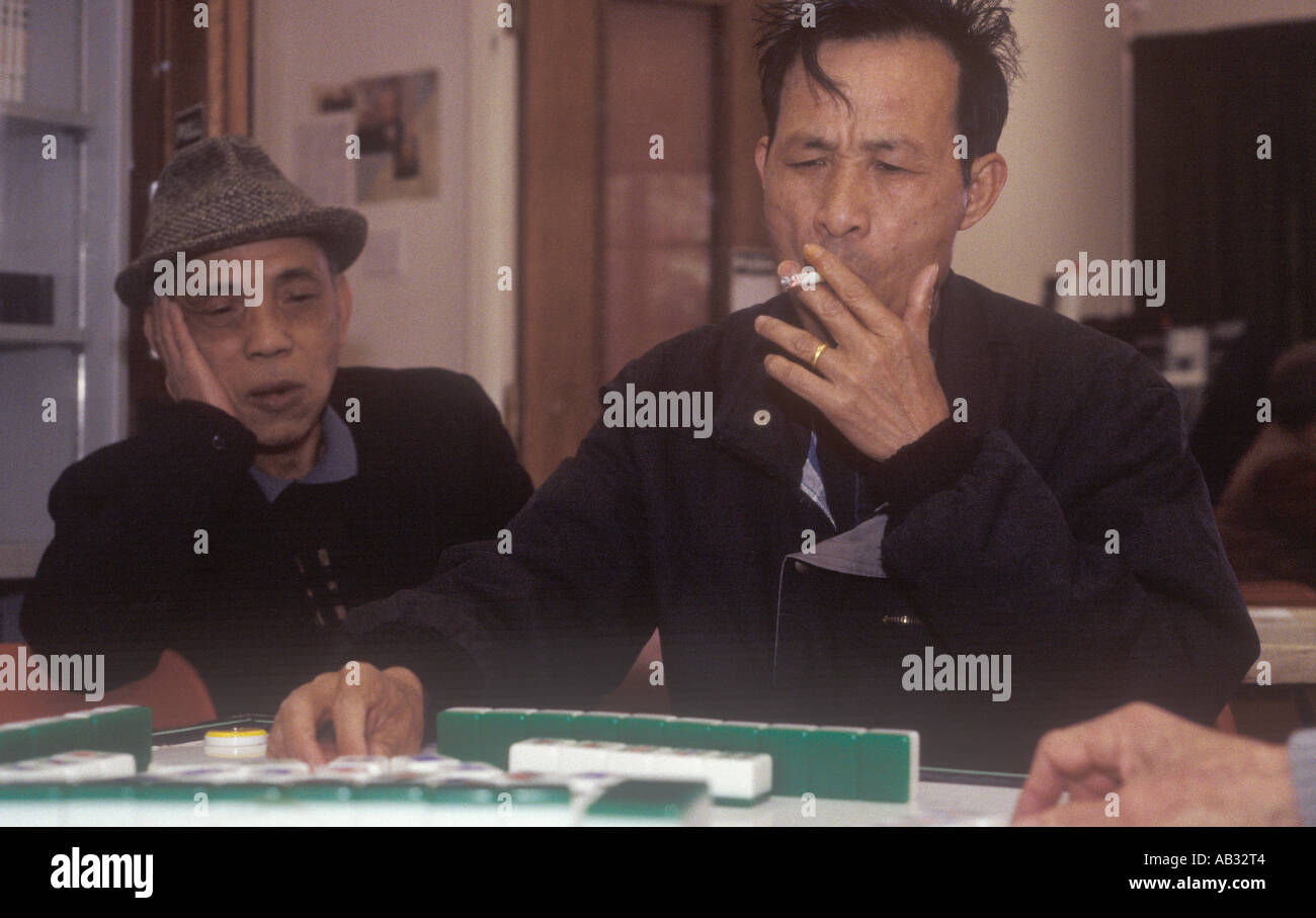 A man smokes whilst playing  the Chinese game of Mah-jong in the Hackney Chinese Community Centre, London, UK. Stock Photo