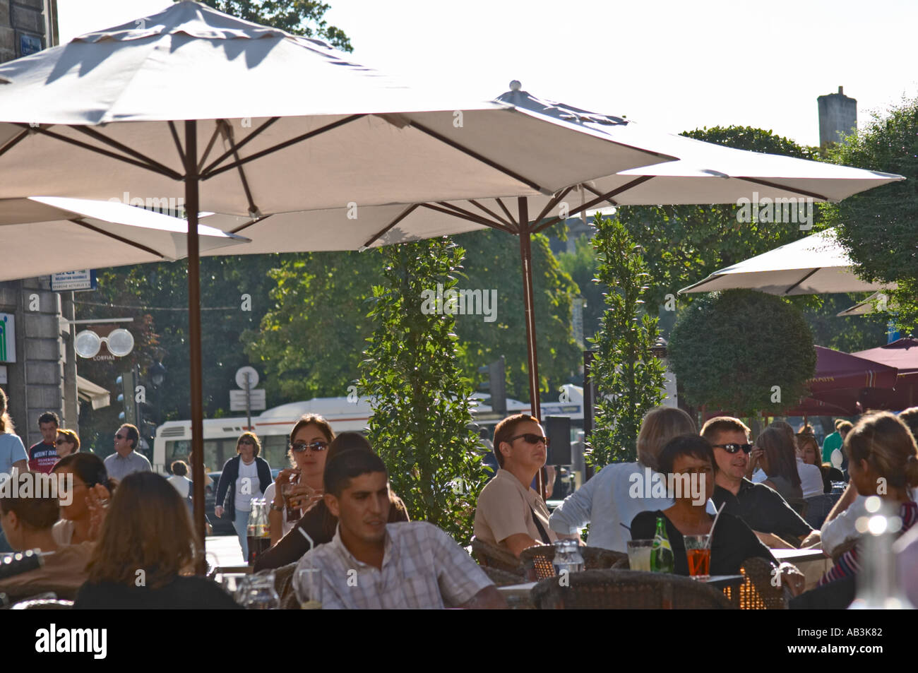 A cafe in Bordeaux city, outside seating terrasse with sun shades parasol,  people drinking and eating Stock Photo - Alamy