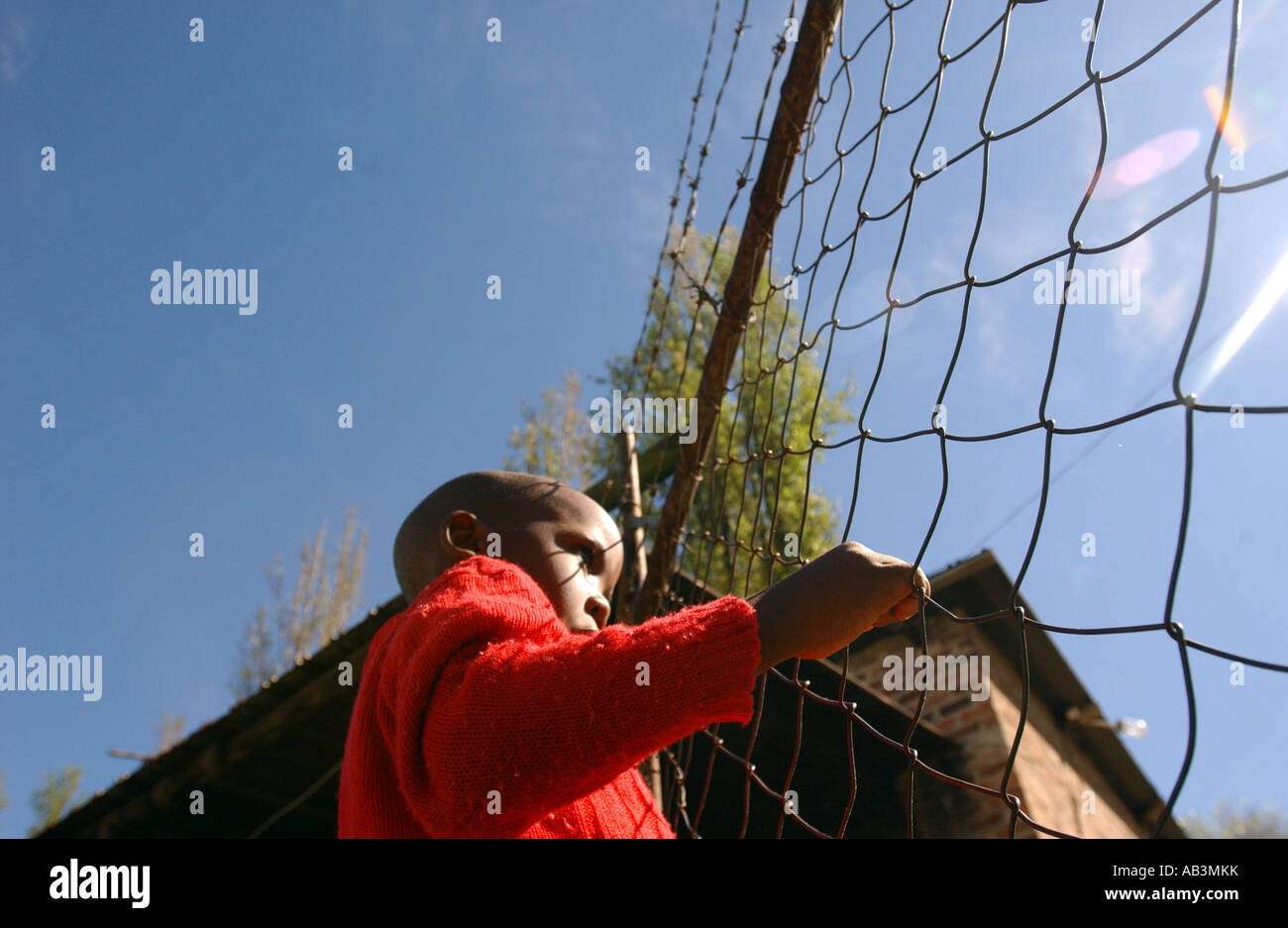 Child looks out over a wire fence in an orphanage in Maseru, Lesotho Stock Photo