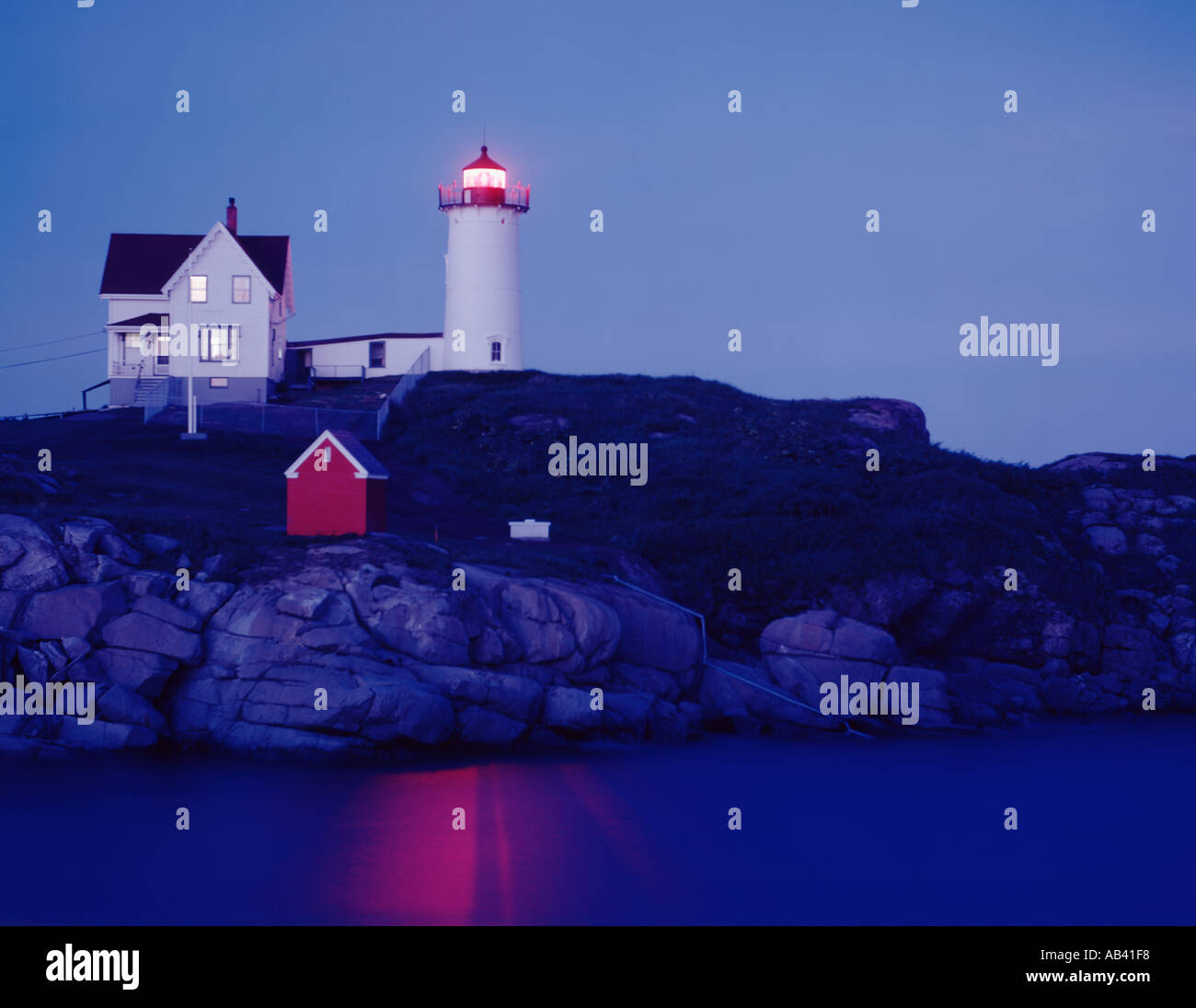 Cape Neddick Nubble lighthouse at Long Sands beach near York Maine seen at dusk with the light shining Stock Photo