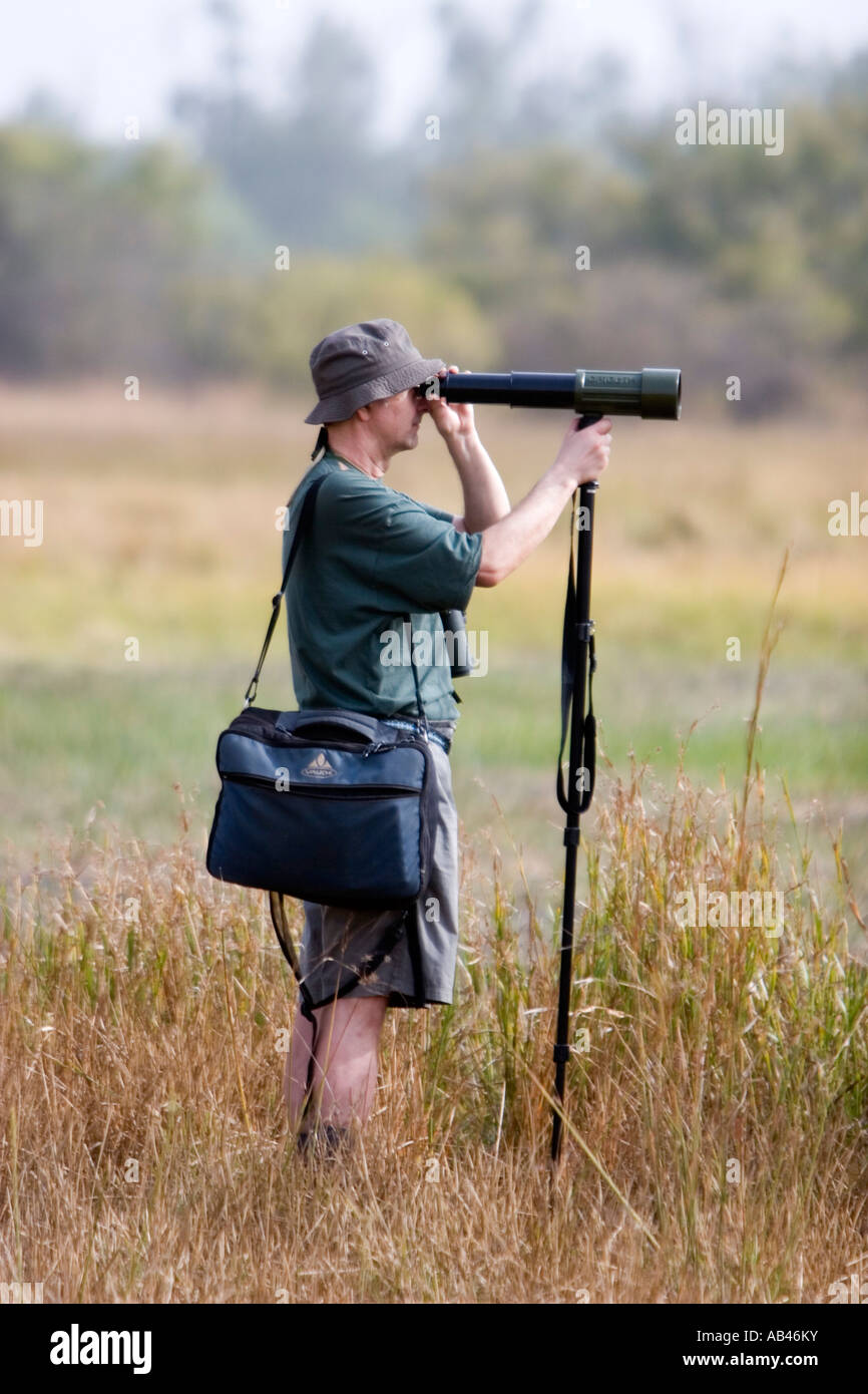 Bird watcher scans grassland mud flats with tlescope on monopod near Tendaba Camp The Gambia Stock Photo