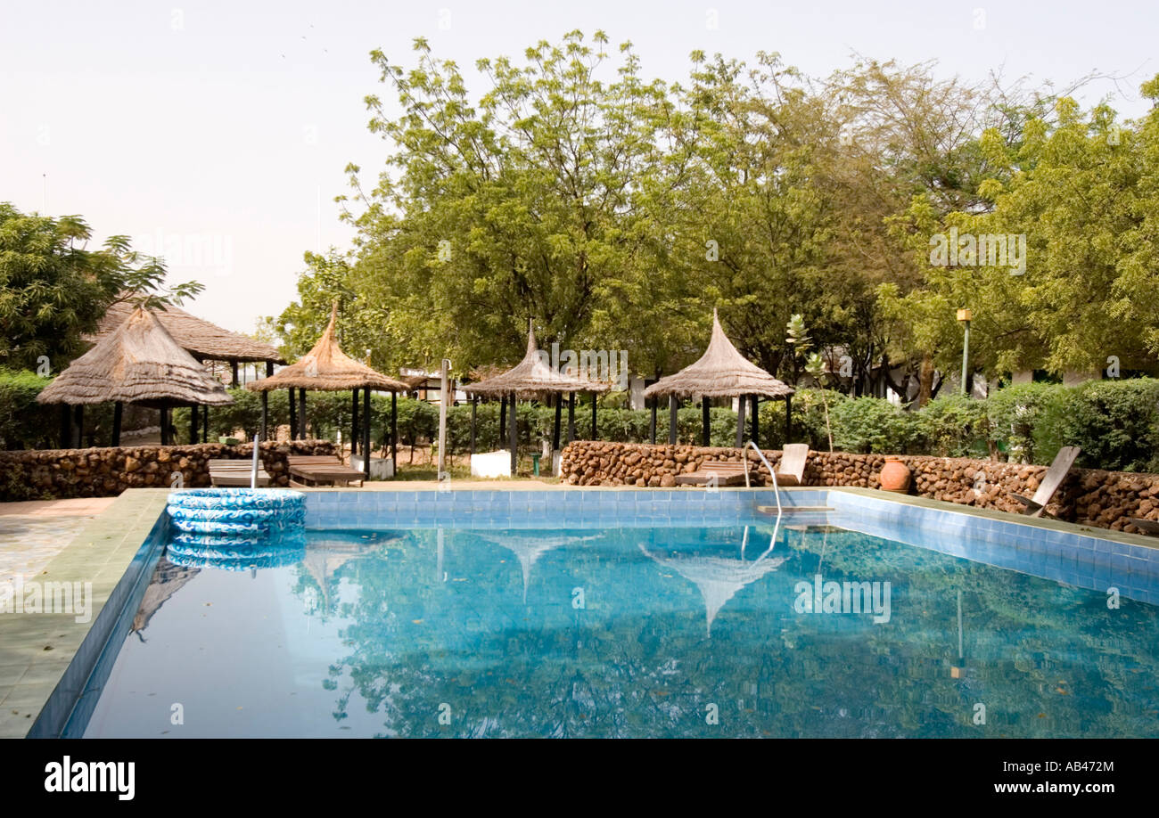 Swimming pool with traditional style thatch umbrellas Tendaba Camp The Gambia Stock Photo