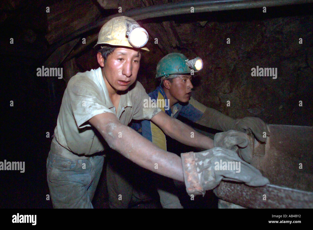Two local men push a silver ore bucket through a tunnel in the silver mine at Potosi, Bolivia. Stock Photo
