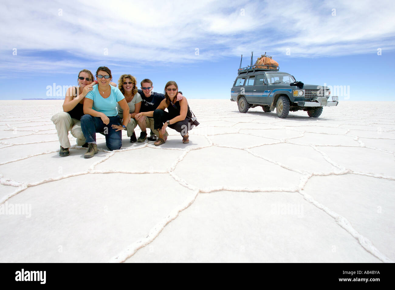 A group of tourists posing on the Bolivian Salt Flats (Salar de Uyuni) during a jeep safari. Stock Photo