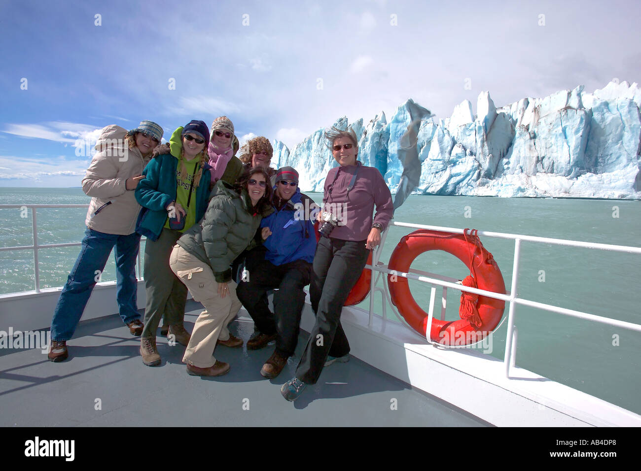 Tourists pose for the camera struggling against the wind while on a boat trip visiting the Viedma Glacier. Stock Photo