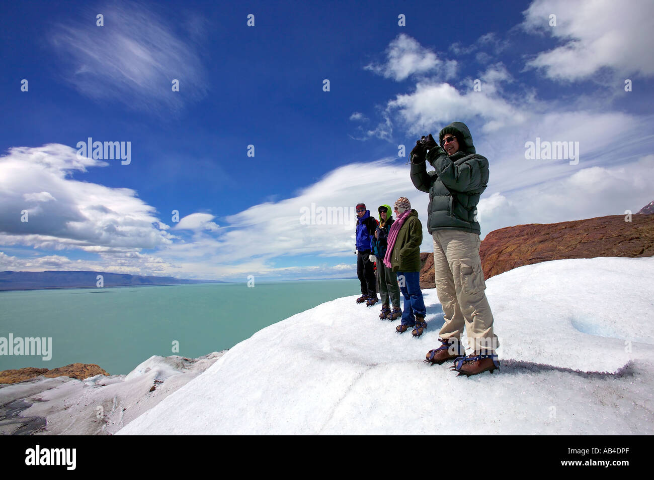 A group of tourists pose for the camera while on a glacier walking trip on the Viedma Glacier. Stock Photo