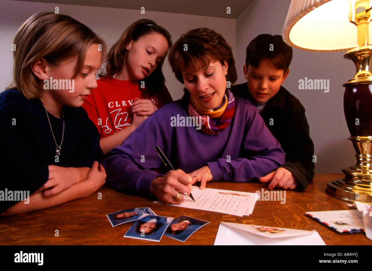 Woman in United States writes letter with her 3 children looking on Stock Photo