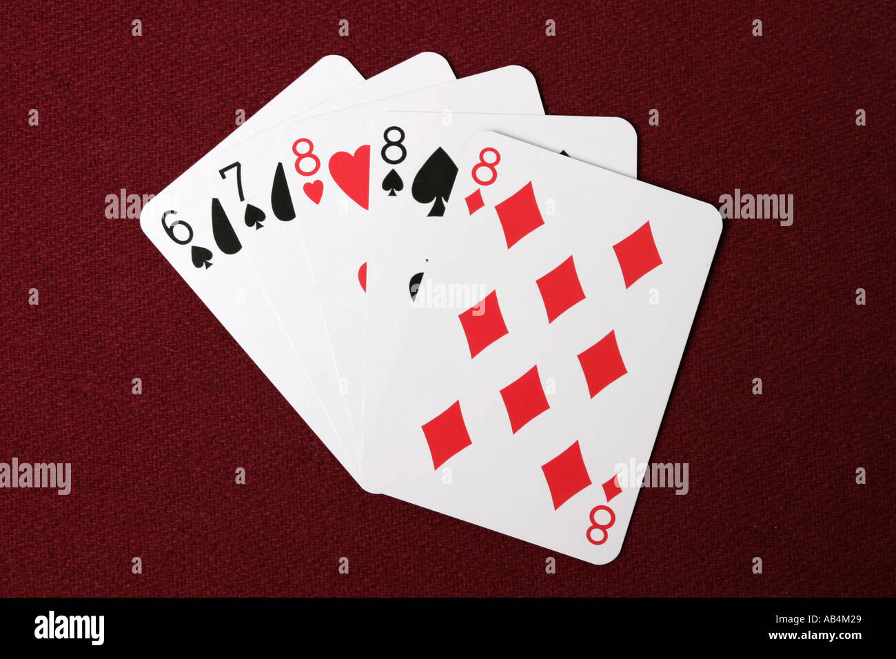 Three of a kind poker hand cards fanned out on a red dealers table