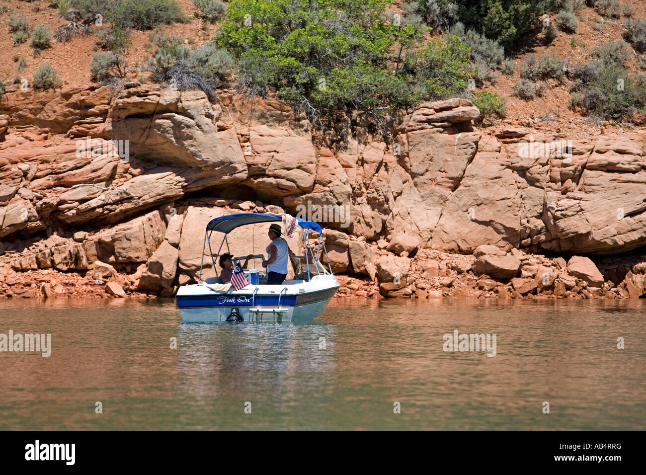 Boat couple under awning rocky ledge. High altitude fishing and