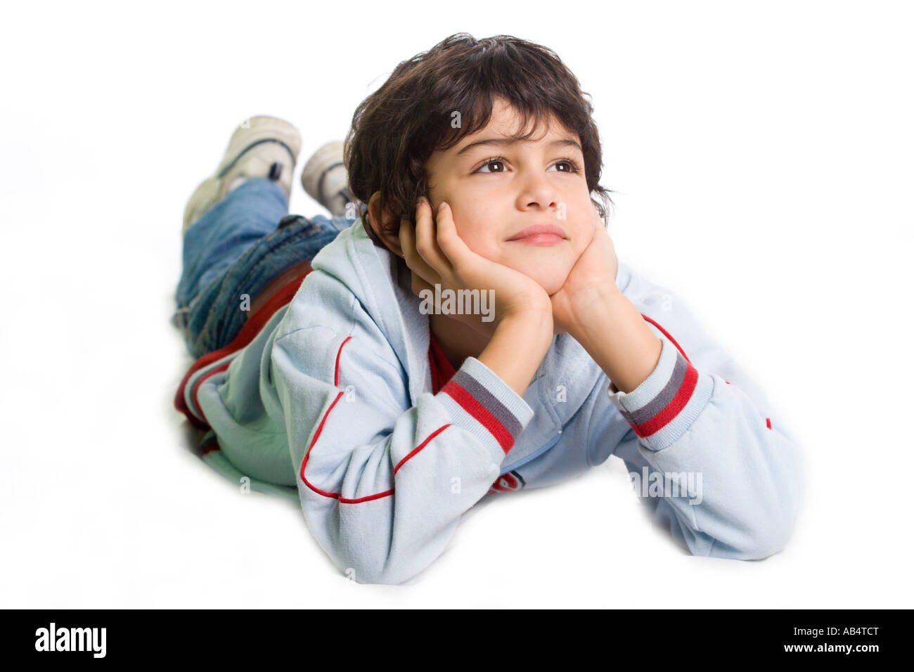 Young boy laid down on the floor in a thoughtful pose like he was wishing something Studio shot isolated on white background Stock Photo