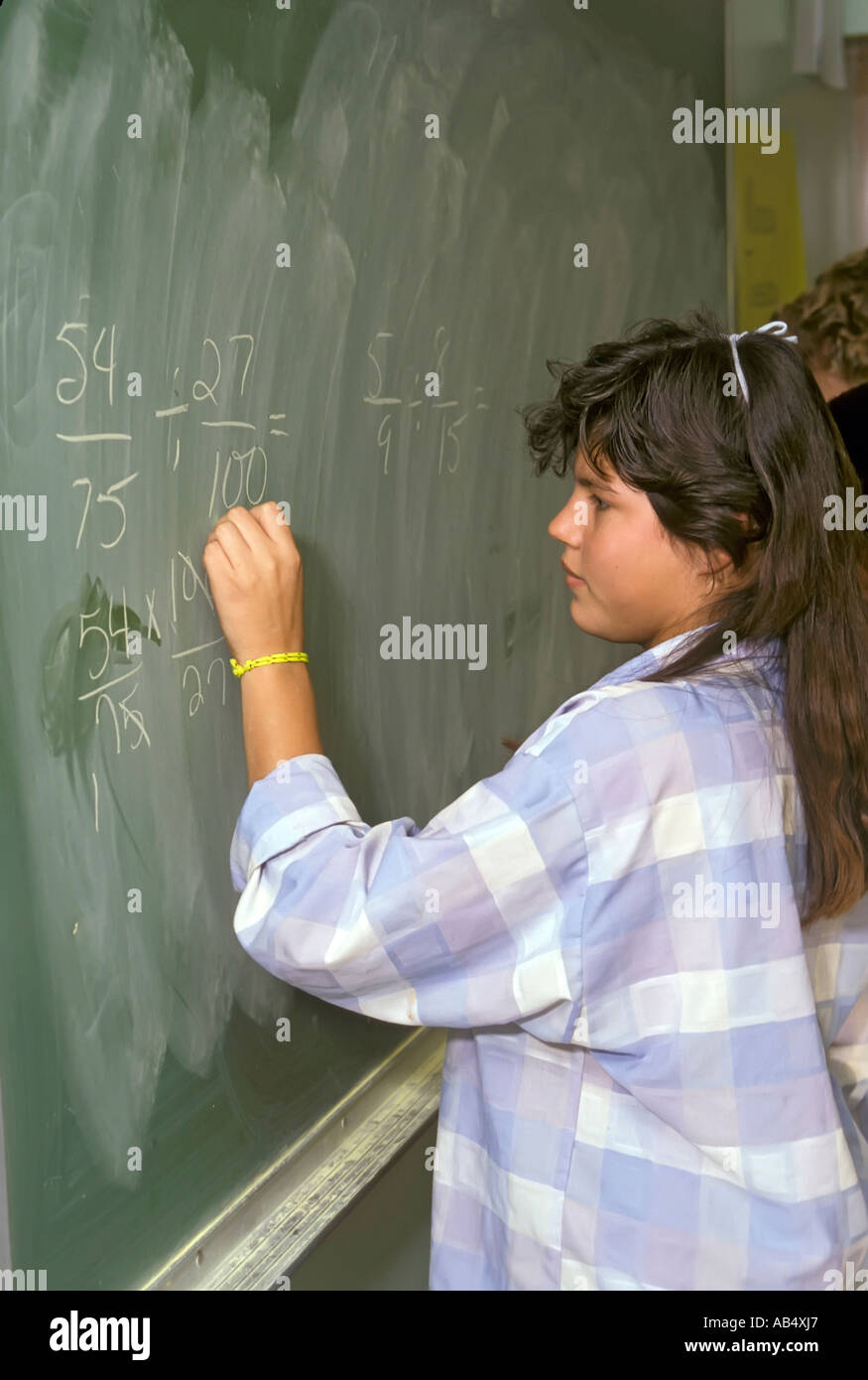 Hispanic Latino female student works on math problems on the blackboard during class Stock Photo