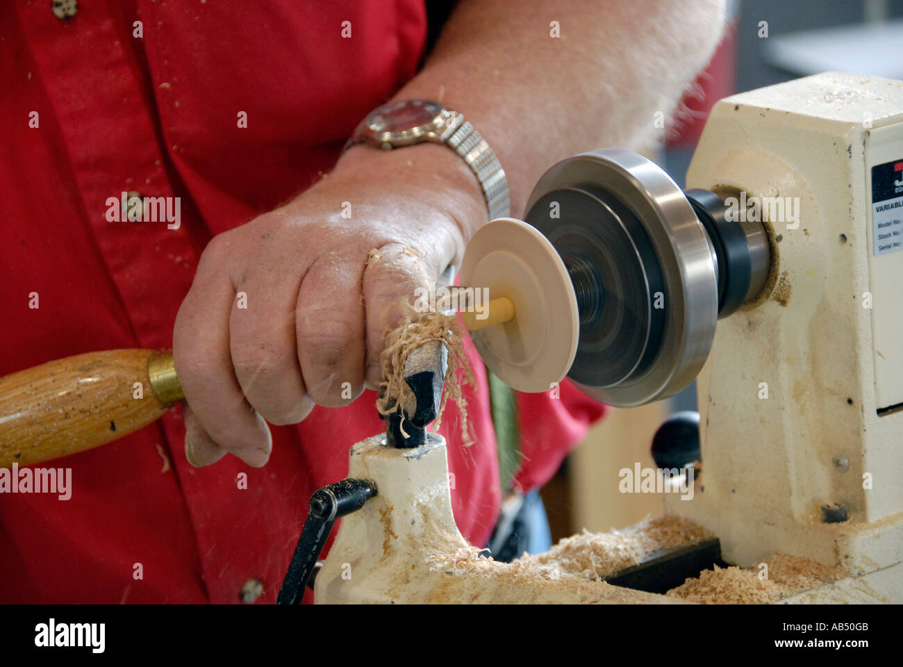 Male pursuing hobby of woodworking by carving a piece of spinning wood on a lathe Stock Photo