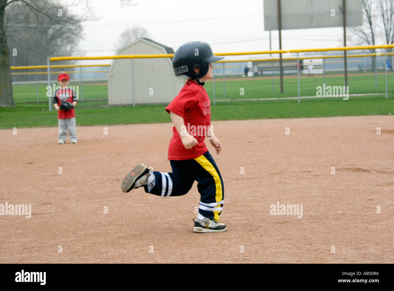5 year old running wearing a protective helmet and tennis shoes Stock