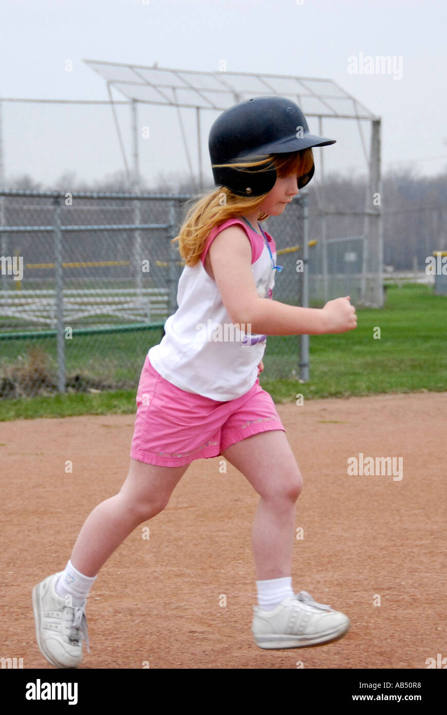 5 year old running wearing a protective helmet and tennis shoes Stock