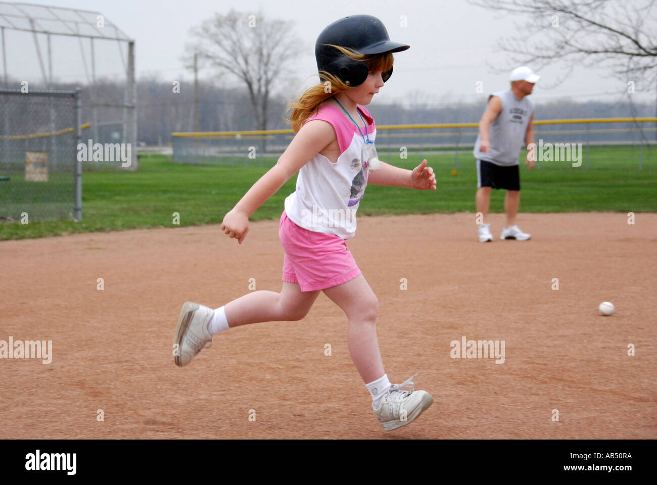 5 year old running wearing a protective helmet and tennis shoes Stock