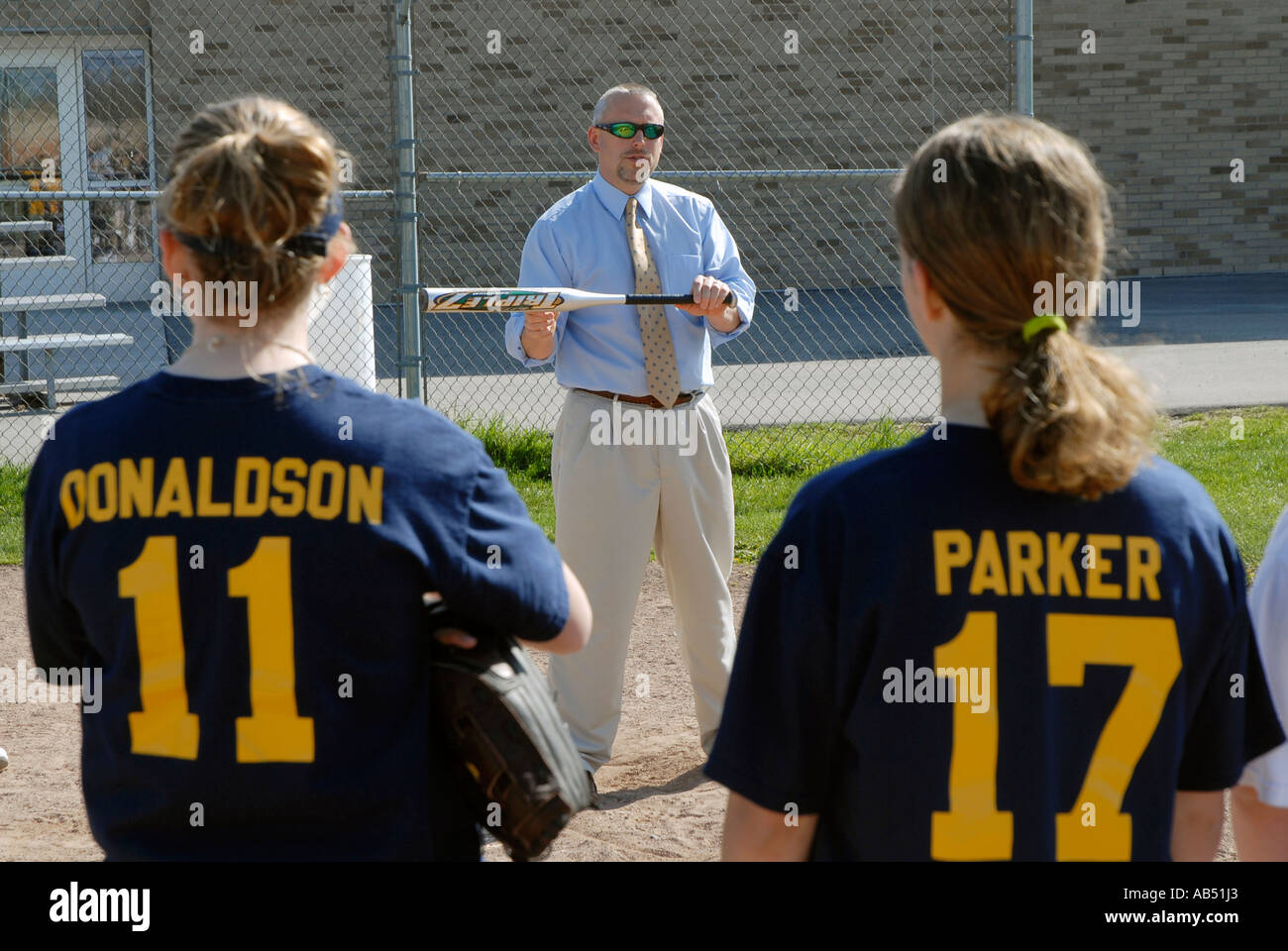 Softball coach explains the concept of bunting the ball to his middle school girls softball team Stock Photo