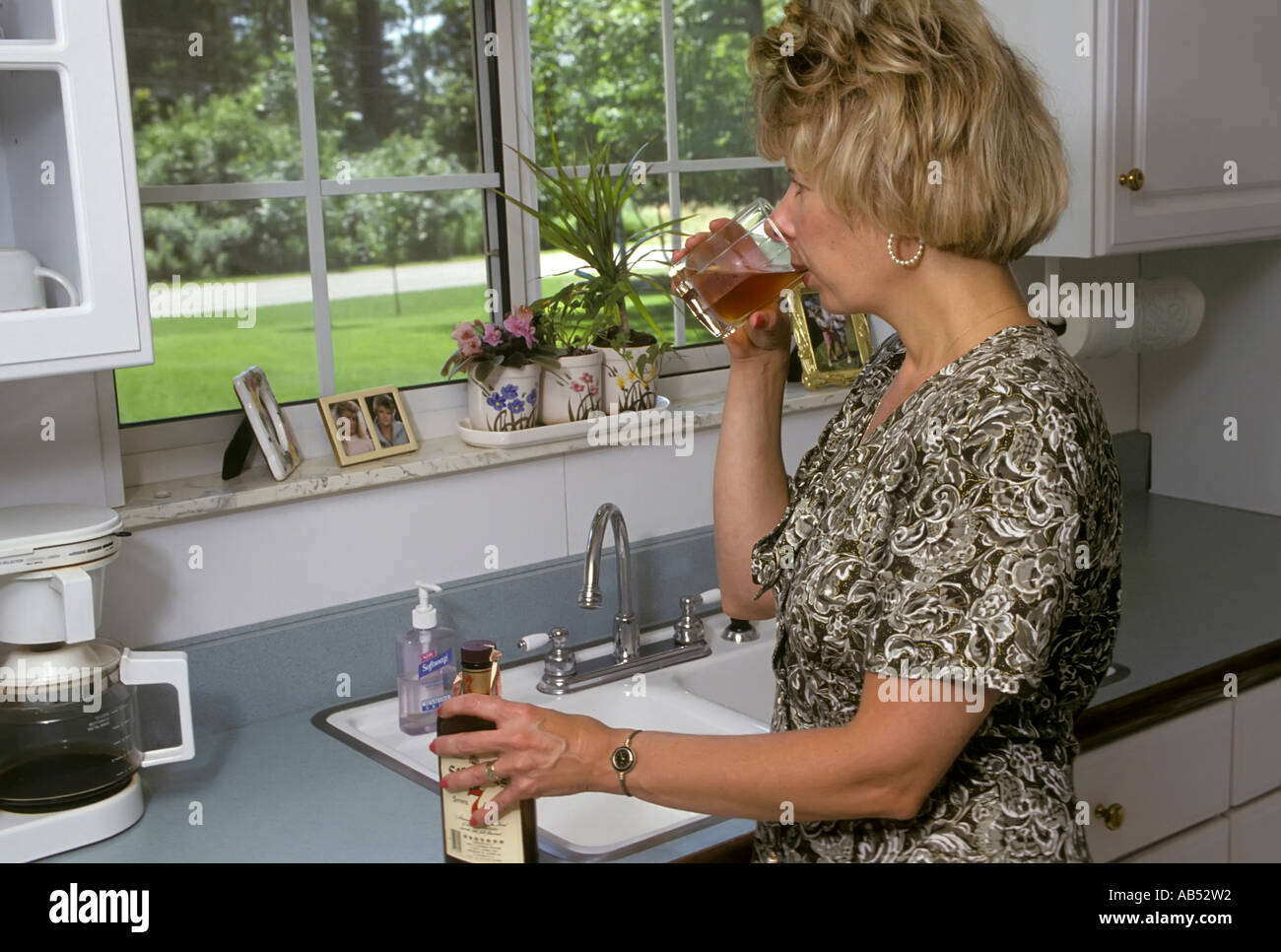 Adult female woman drinking alcohol during the daytime at home Stock Photo