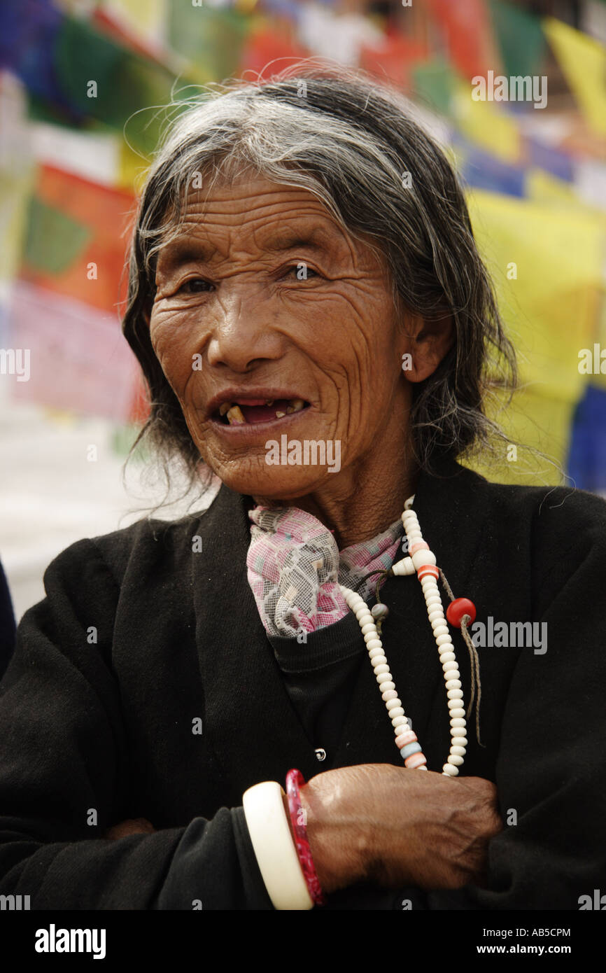 Old Nepalese lady of the Gurung caste, prayer flags in the back, Nepal 2007 Stock Photo