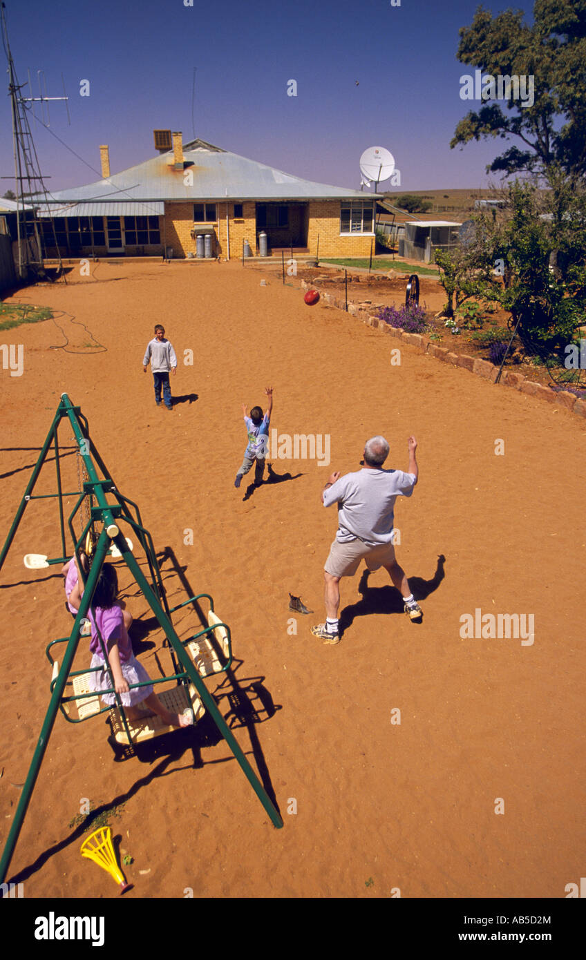 Family playing Australian Rules football in backyard, Langidoon Station, near Broken Hill, New South Wales, Australia, vertical, Stock Photo