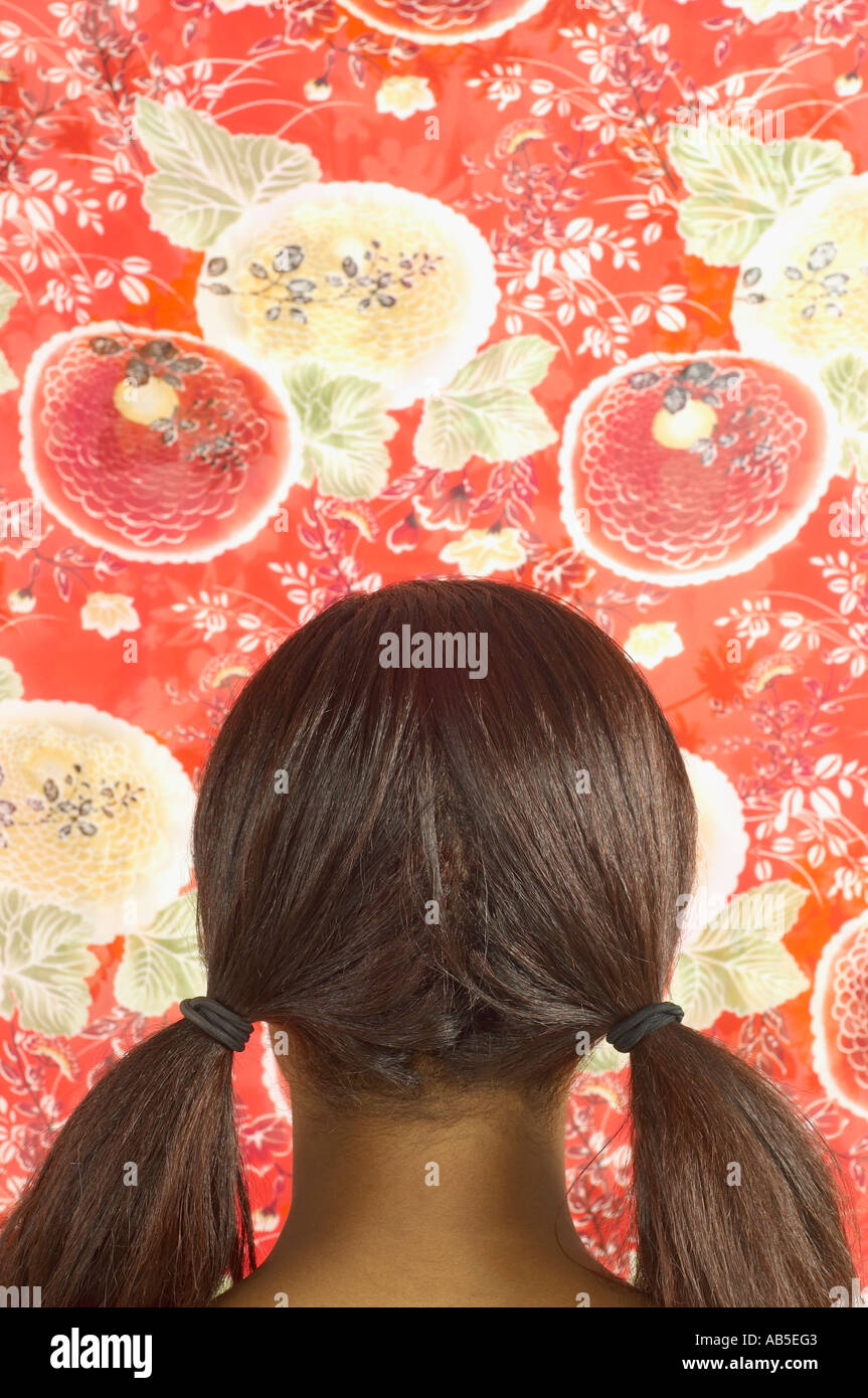 Young woman in pigtails looking at wallpaper Stock Photo