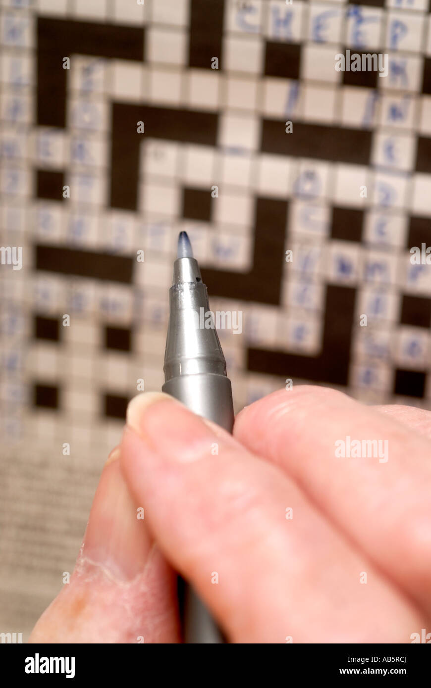 Elderly lady s hand holding pen while doing crossword Stock Photo Alamy