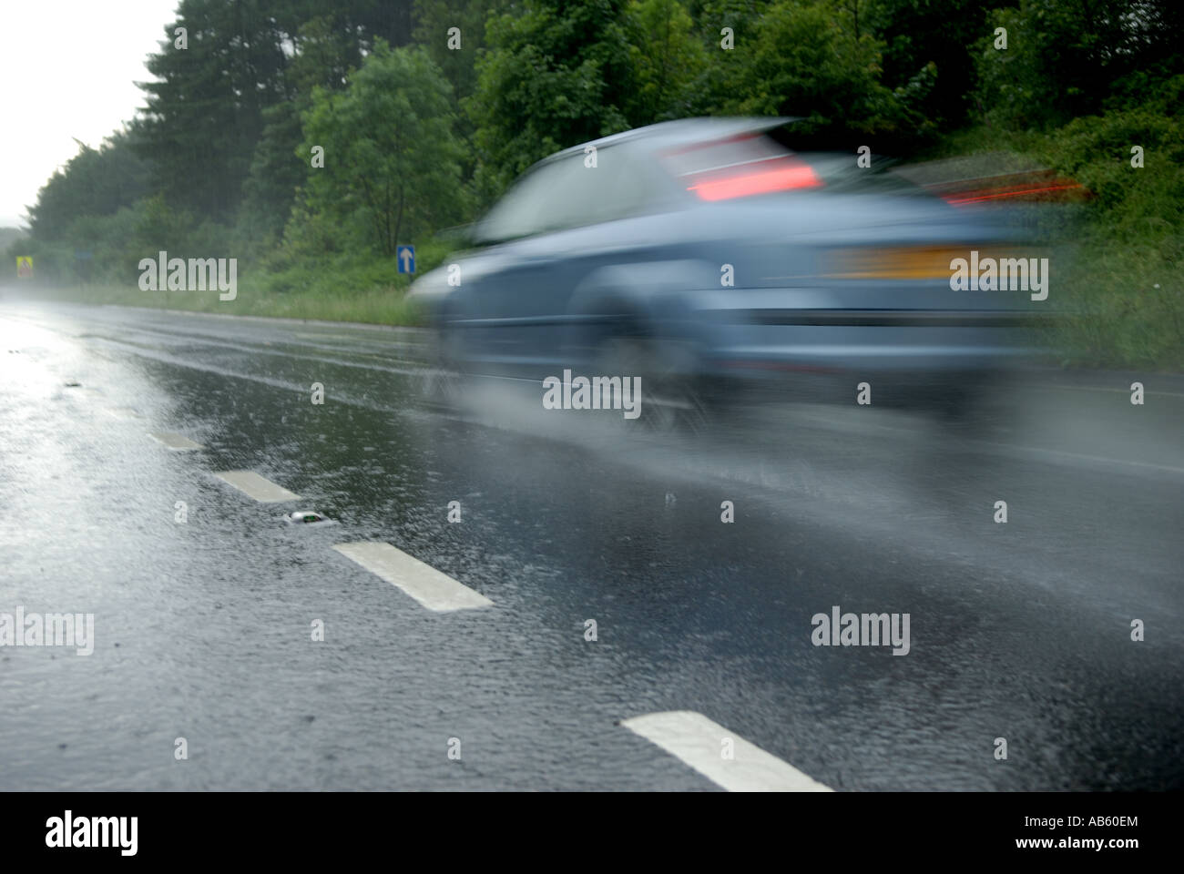 Speeding car on wet road surface Stock Photo - Alamy